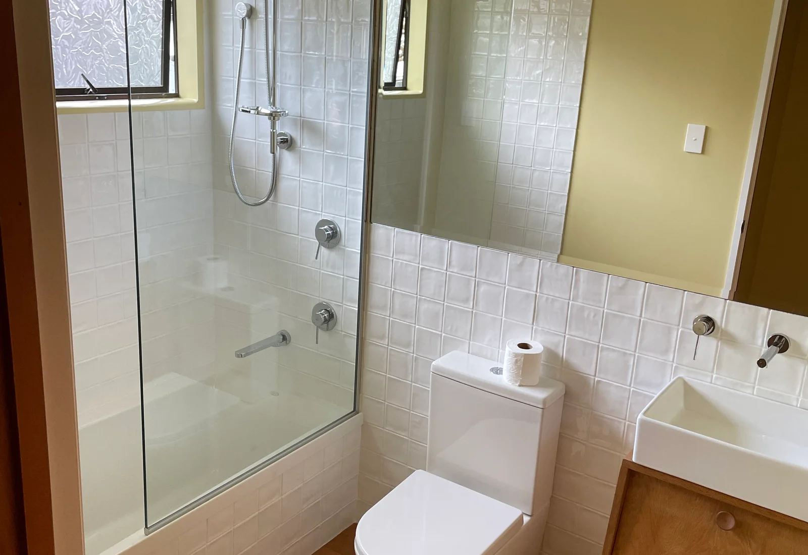 A renovated bathroom on Cliff Street with white tiling and glass shower screen