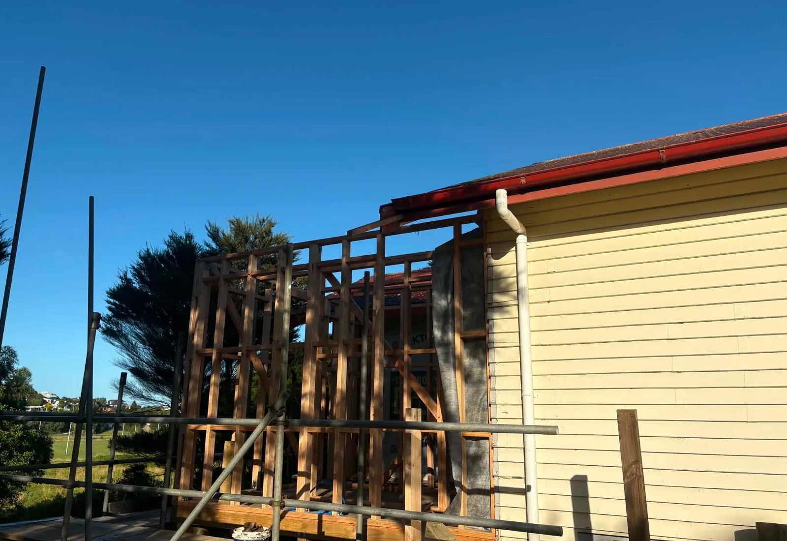 Early framing of the new wing going up alongside the original single-storey house