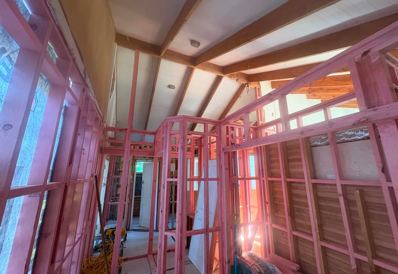 Inside the new upstairs space, with the vaulted ceiling framed and a doorway through to the original home