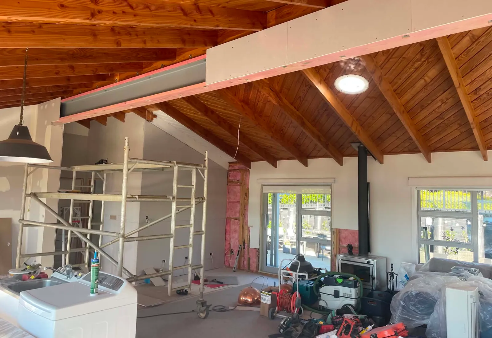 The steel beam in place above the new opening, encased and painted, with scaffolding still up while finishing work continues